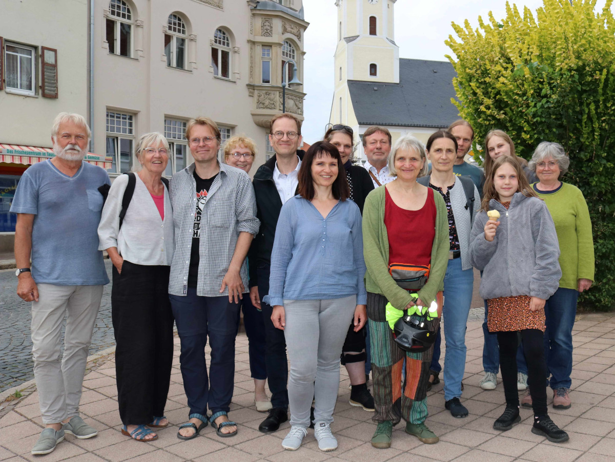 Eine Gruppe von etwa 15 Menschen zwischen 14 und 74 - die Mitglieder der Klima-Initiative Taucha auf dem Markt, im Hintergrund die Kirche St. Moritz