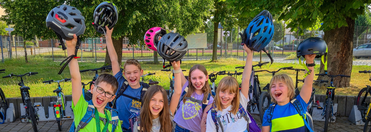 Eine Handvoll Kinder mit Fahrradhelmen winken in die Kamera: STADTRADELN 2025